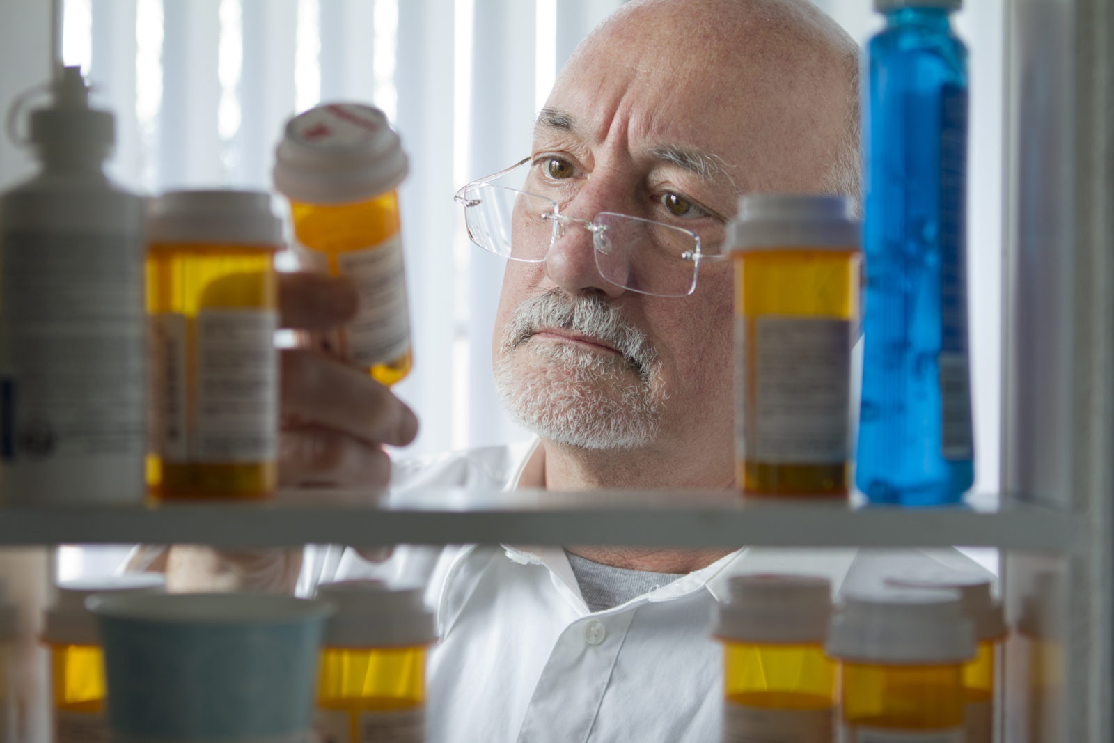 Senior man looking at prescription drugs in his medicine cabinet