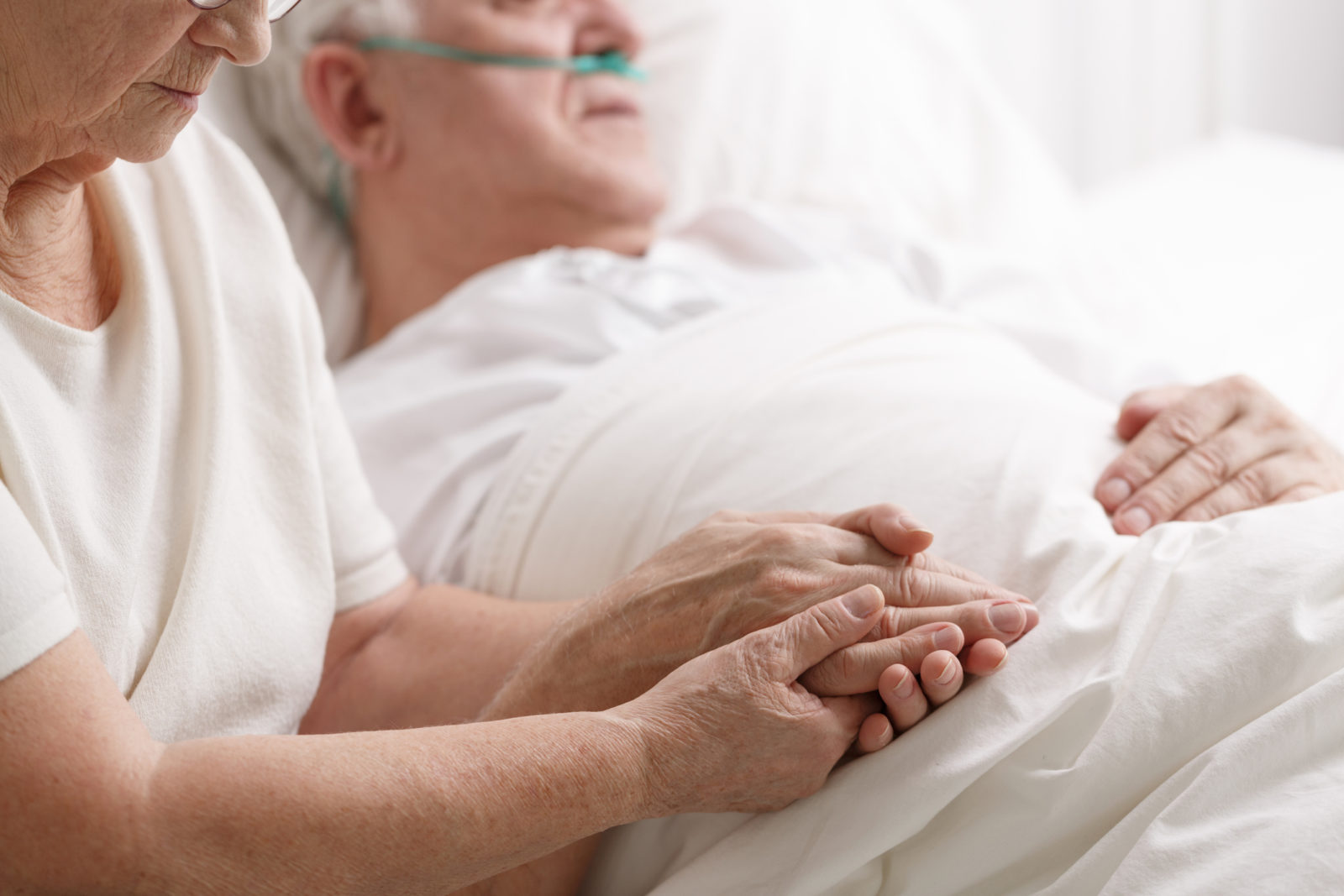 Wife holding comatose husband's hand in hospital