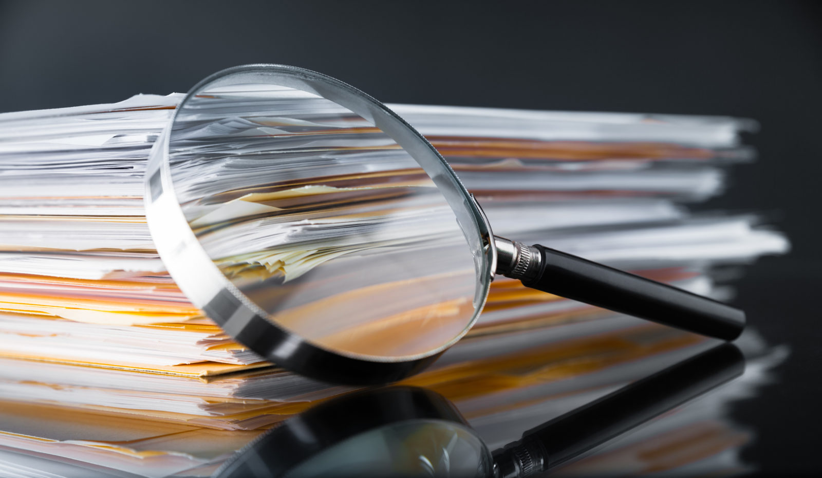 stack of documents and magnifying glass