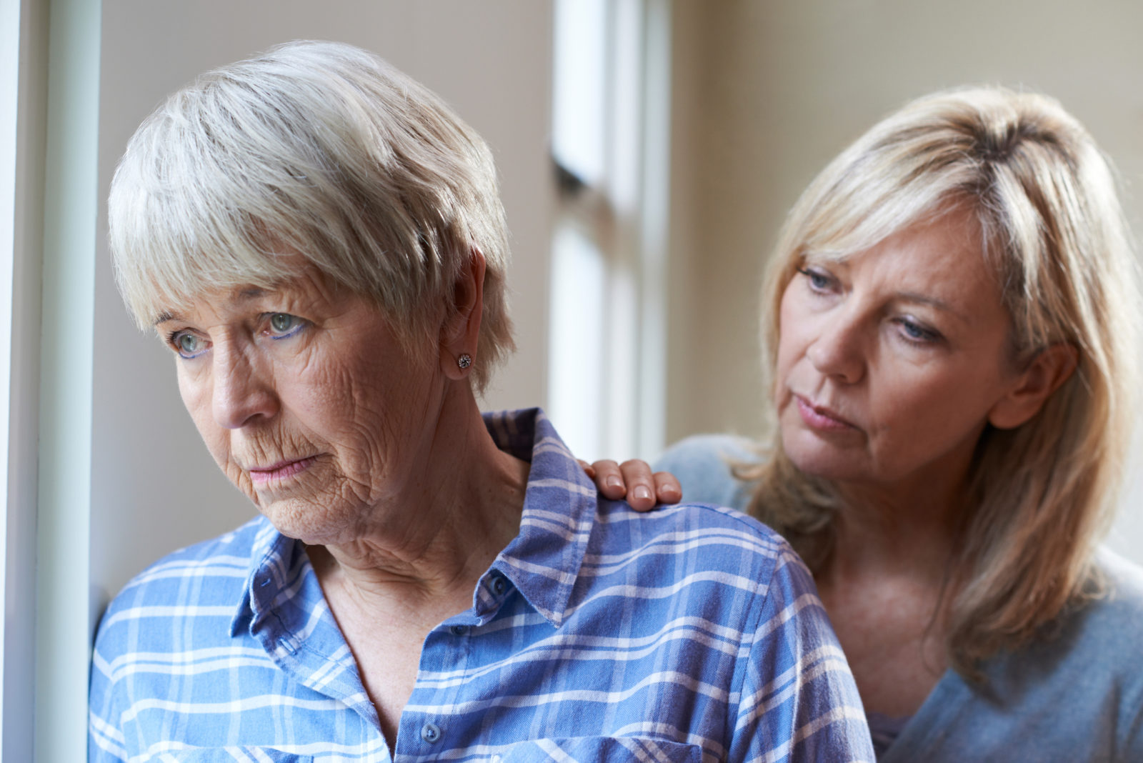 daughter comforting elderly mother suffering from dementia and depression