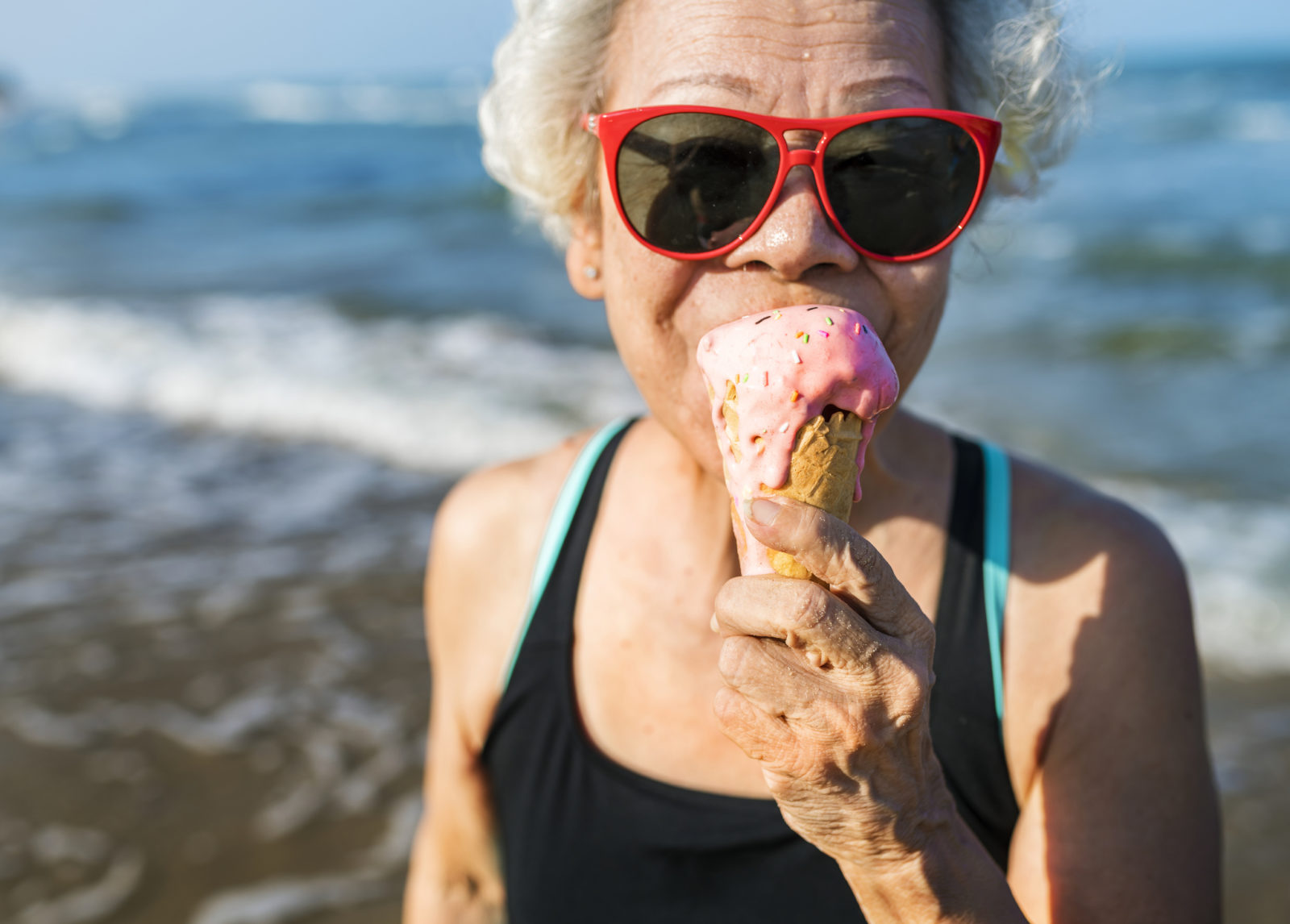 Older woman eating ice cream cone on the beach