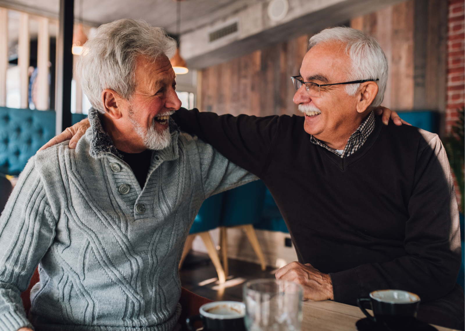 two elderly gentleman arms around each other